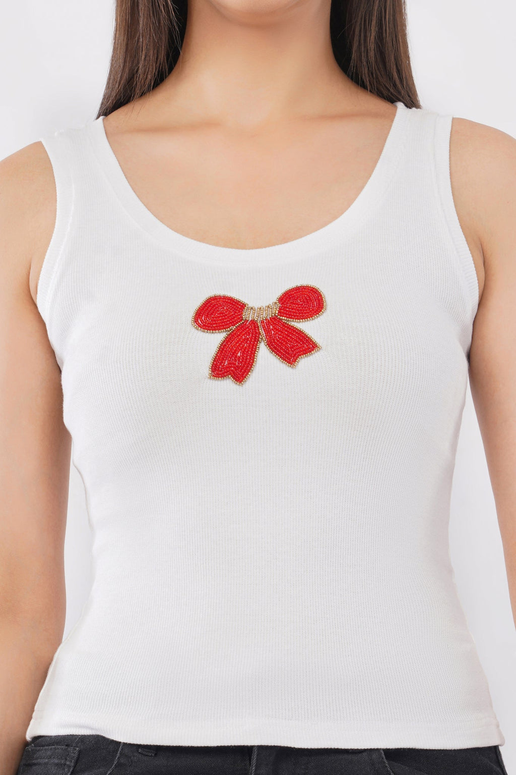 Woman wearing a white cotton ribbed tank top featuring a handcrafted red bow beadwork motif by CherryPop