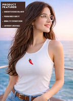 Woman wearing a white tank top with a red chili pepper design by the ocean