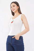 Woman wearing a white tank top with a cherry design and blue jeans on a white background