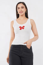 Woman wearing a white cotton ribbed tank top featuring a handcrafted red bow beadwork motif by CherryPop