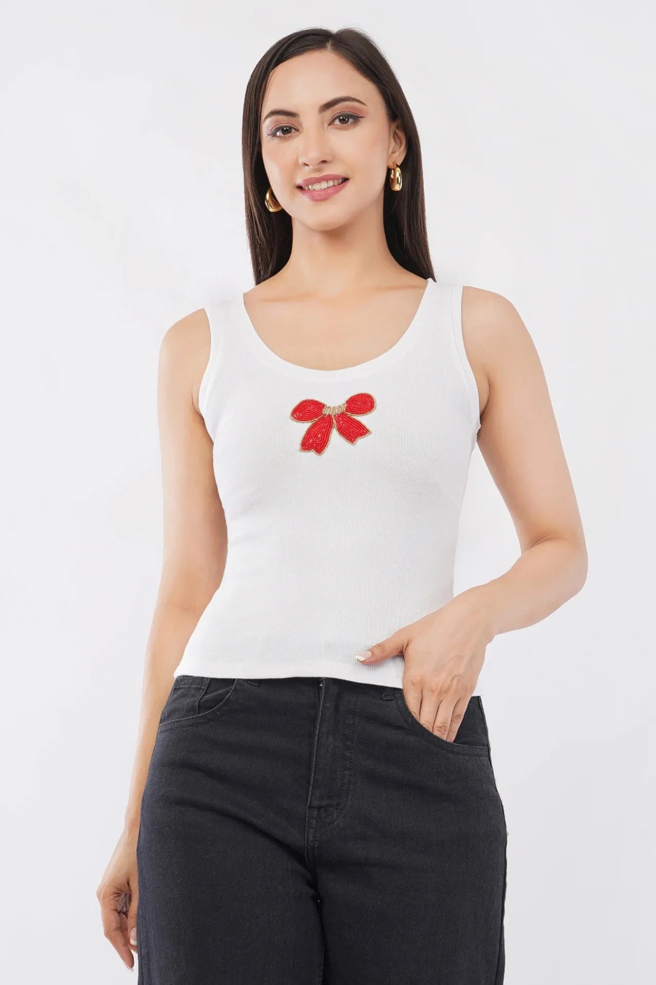 Woman wearing a white cotton ribbed tank top featuring a handcrafted red bow beadwork motif by CherryPop