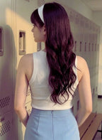 Person with long, wavy hair standing in a locker room.